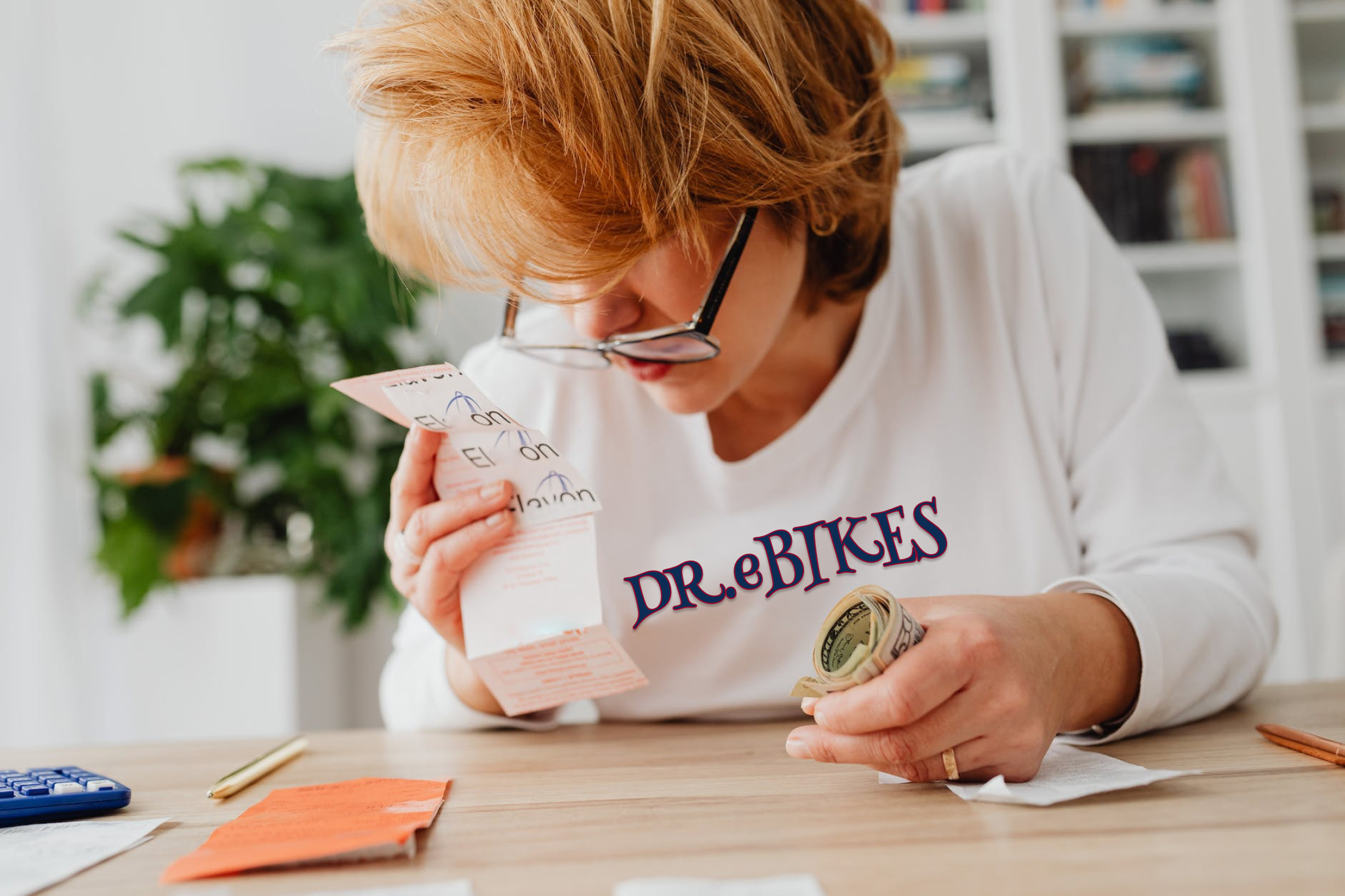 Woman with wearing glasses down on her nose looking at a receipt and money in her hand. With a LOGO of DRebikes on her t-shirt, wondering if it's a good investment.